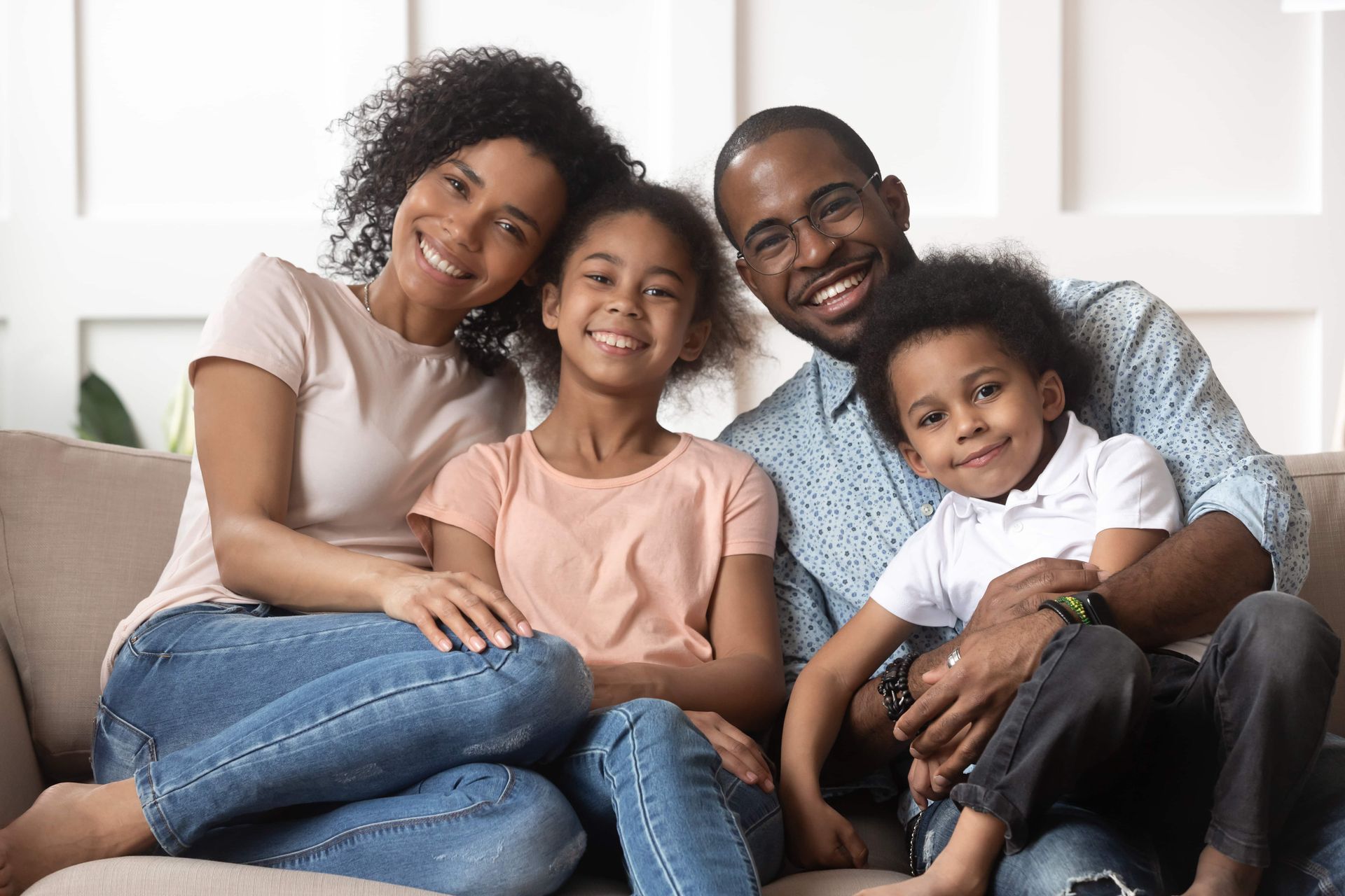 Smiling family of four sitting on a couch in a bright living room