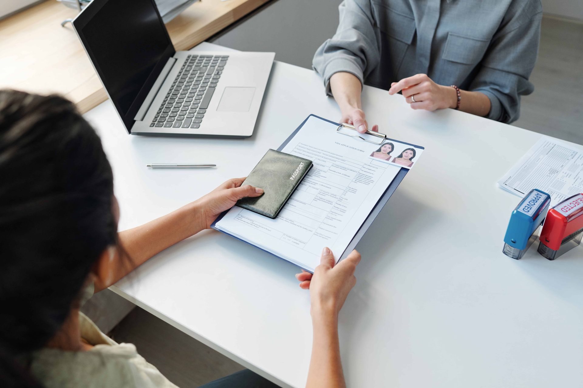 Business meeting with laptop, clipboard, smartphone, and hands reviewing documents on a white table