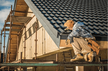 A man is sitting on the roof of a building under construction.