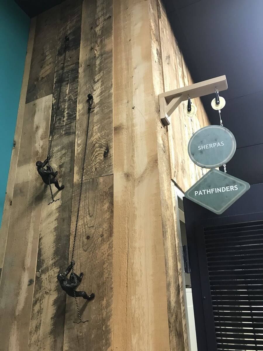 Wooden wall display with hanging climbers and a round sign reading “VON” above another sign.