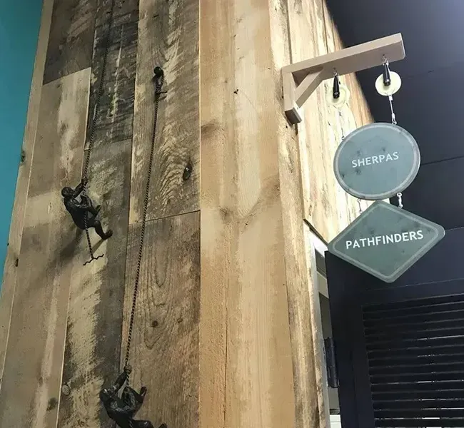 Rustic wooden wall with hanging shoes and a round sign near a doorway