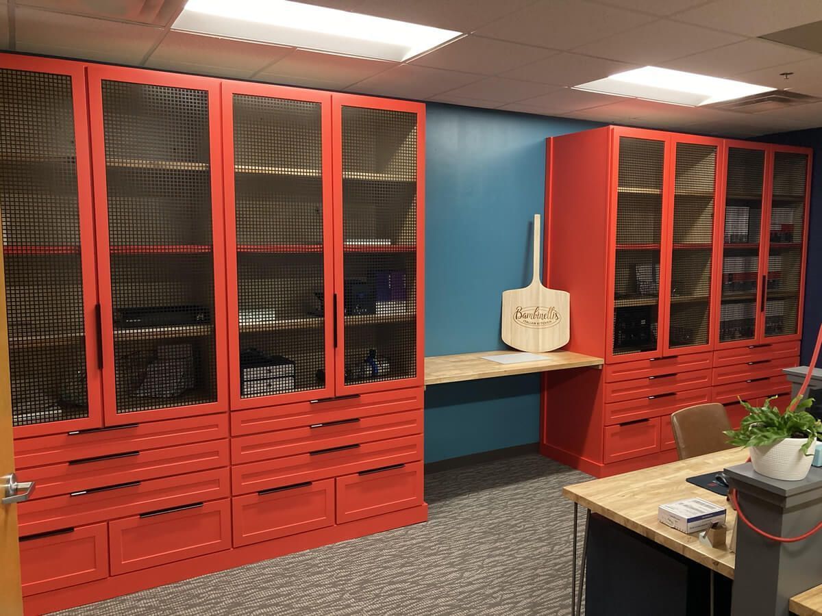 Red storage cabinets with glass doors in a room with blue walls and a desk in the foreground