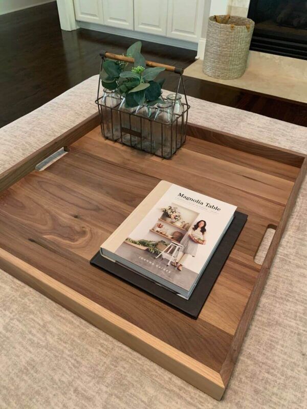 Wooden tray on a beige sofa table with a magazine and a small potted plant centerpiece
