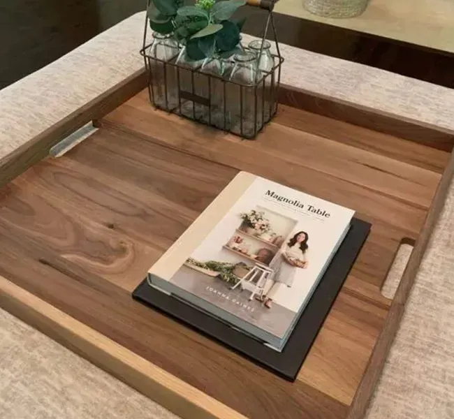 Wooden tray on a beige sofa table with a magazine and a small potted plant centerpiece