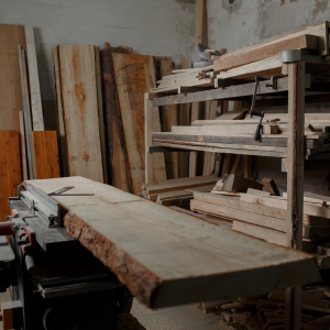 Woodworking shop with stacked lumber and a large plank on a saw table