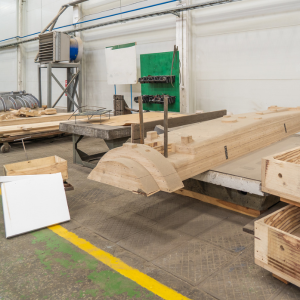 Woodworking shop with large timber beams, a saw table, and stacked lumber on pallets