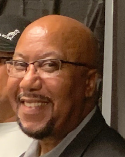 Smiling man in glasses and a dark suit, turned slightly toward the camera.