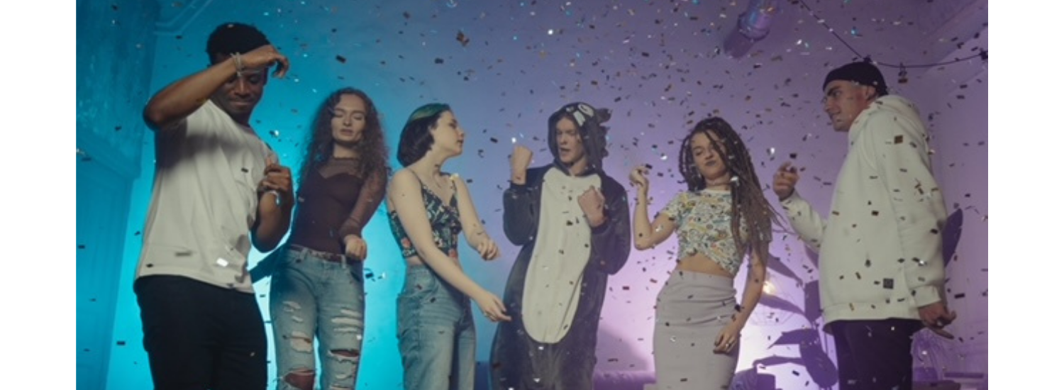 Six people celebrating with confetti in colorful party lighting