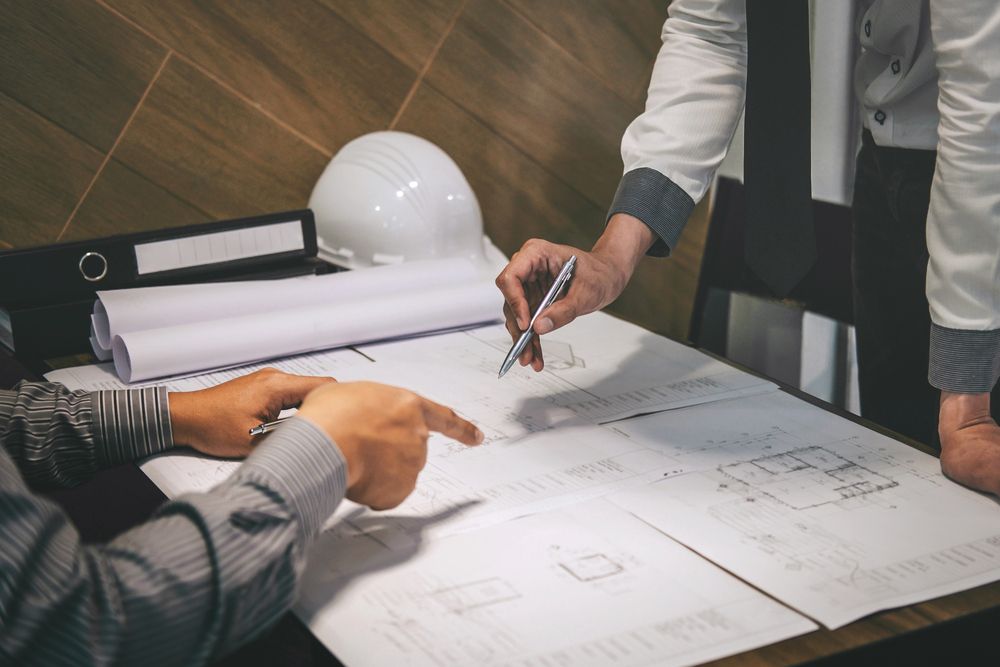 Ufficio moderno open space con scrivanie, computer, sedie nere, pavimenti in legno e scaffalature lungo le pareti.