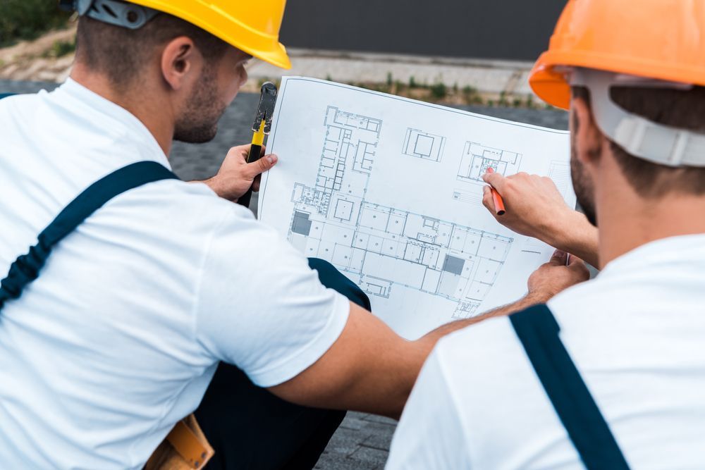 Due operai edili con il casco esaminano i progetti in un cantiere.