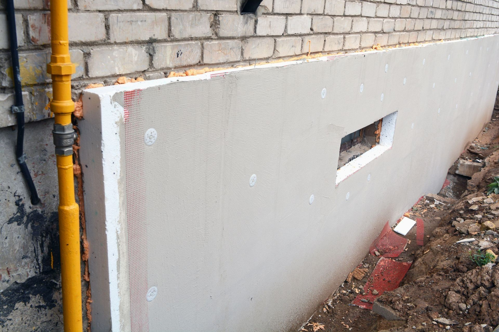 Gray panel leaning against a brick wall beside a yellow pipe in an outdoor construction area Gray panel leaning against a brick wall beside a yellow pipe in an outdoor construction area