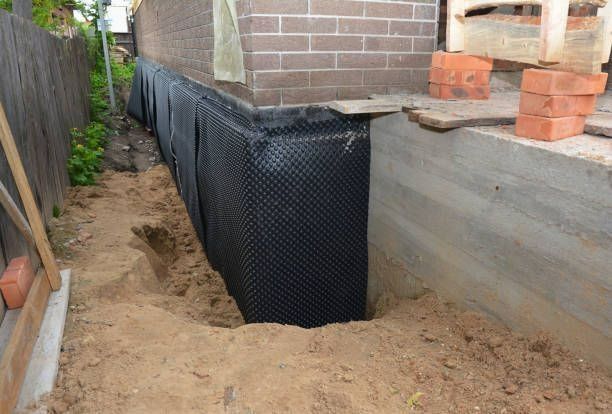 Black membrane applied to exposed foundation wall during basement waterproofing work. Black membrane applied to exposed foundation wall during basement waterproofing work.