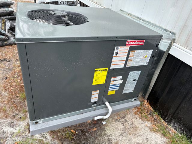 Outdoor HVAC unit beside a building, with a top fan and visible service labels.