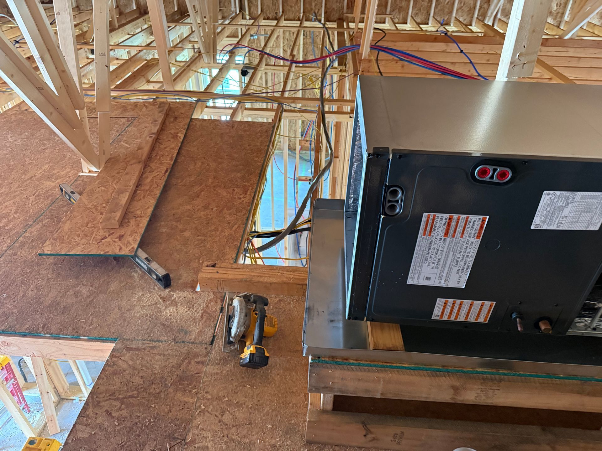 HVAC unit installed in an unfinished attic with exposed wooden framing and ductwork