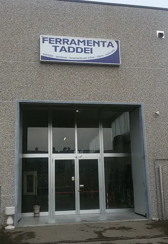 Ingresso del negozio Ferramenta Taddei con porta a vetri e parete esterna grigia