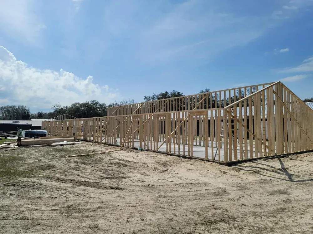 A large wooden structure is being built in a dirt field.