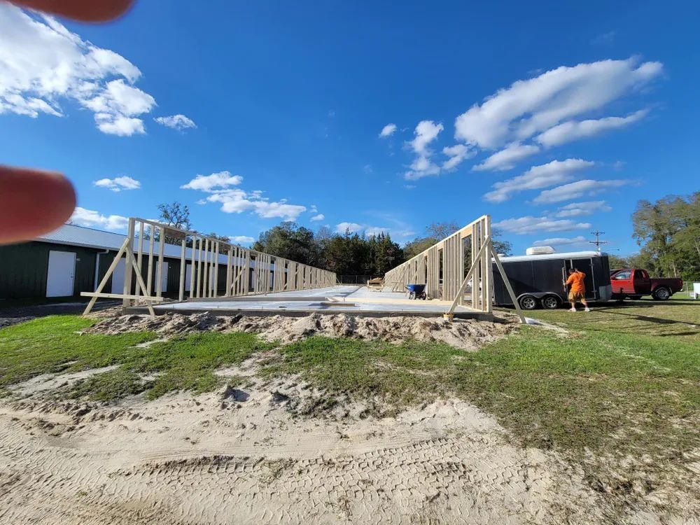 A person is holding a piece of wood in front of a building under construction.