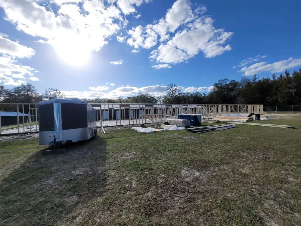 A trailer is parked in a grassy field in front of a building under construction.