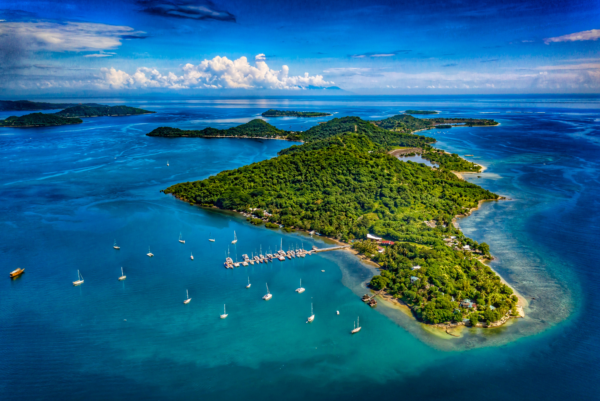 An aerial view of a small island in the middle of the ocean surrounded by boats.