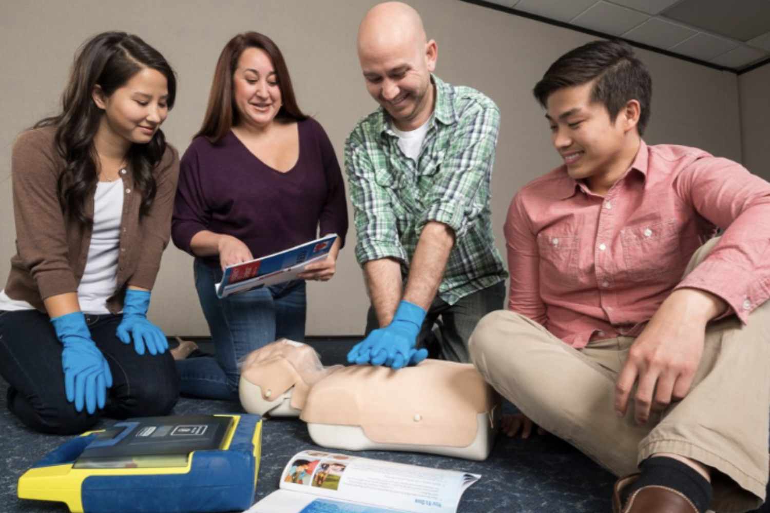 A group of people are practicing first aid on a mannequin.