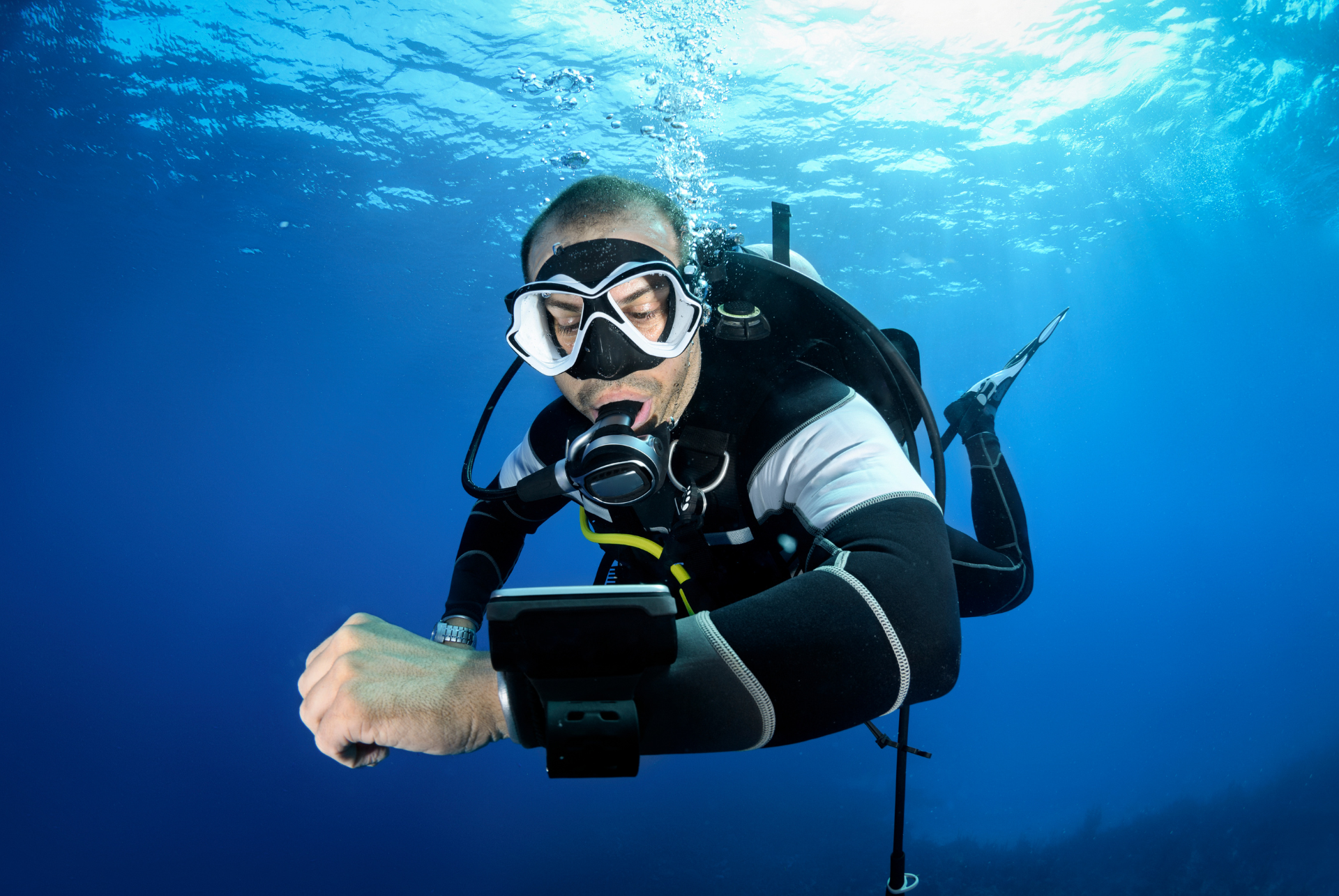 A scuba diver is using a tablet computer underwater.