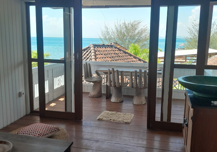 A living room with sliding glass doors leading to a balcony overlooking the ocean.