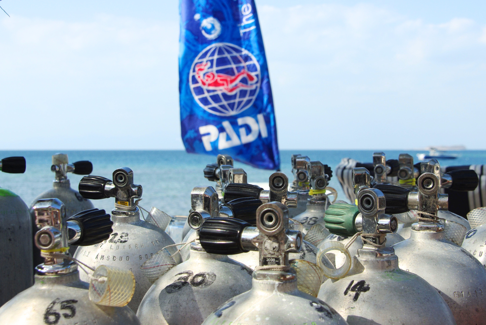 A group of scuba tanks are lined up in front of a flag that says padi