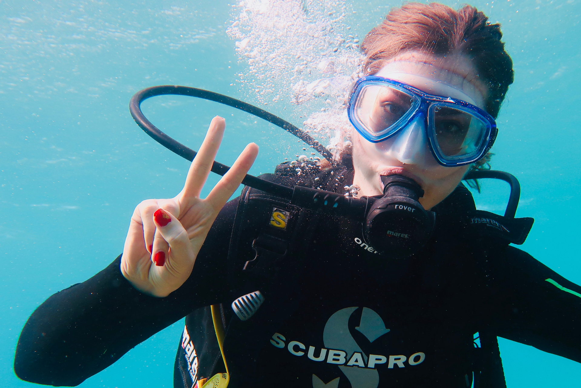 A woman in a scubapro wetsuit is giving a peace sign