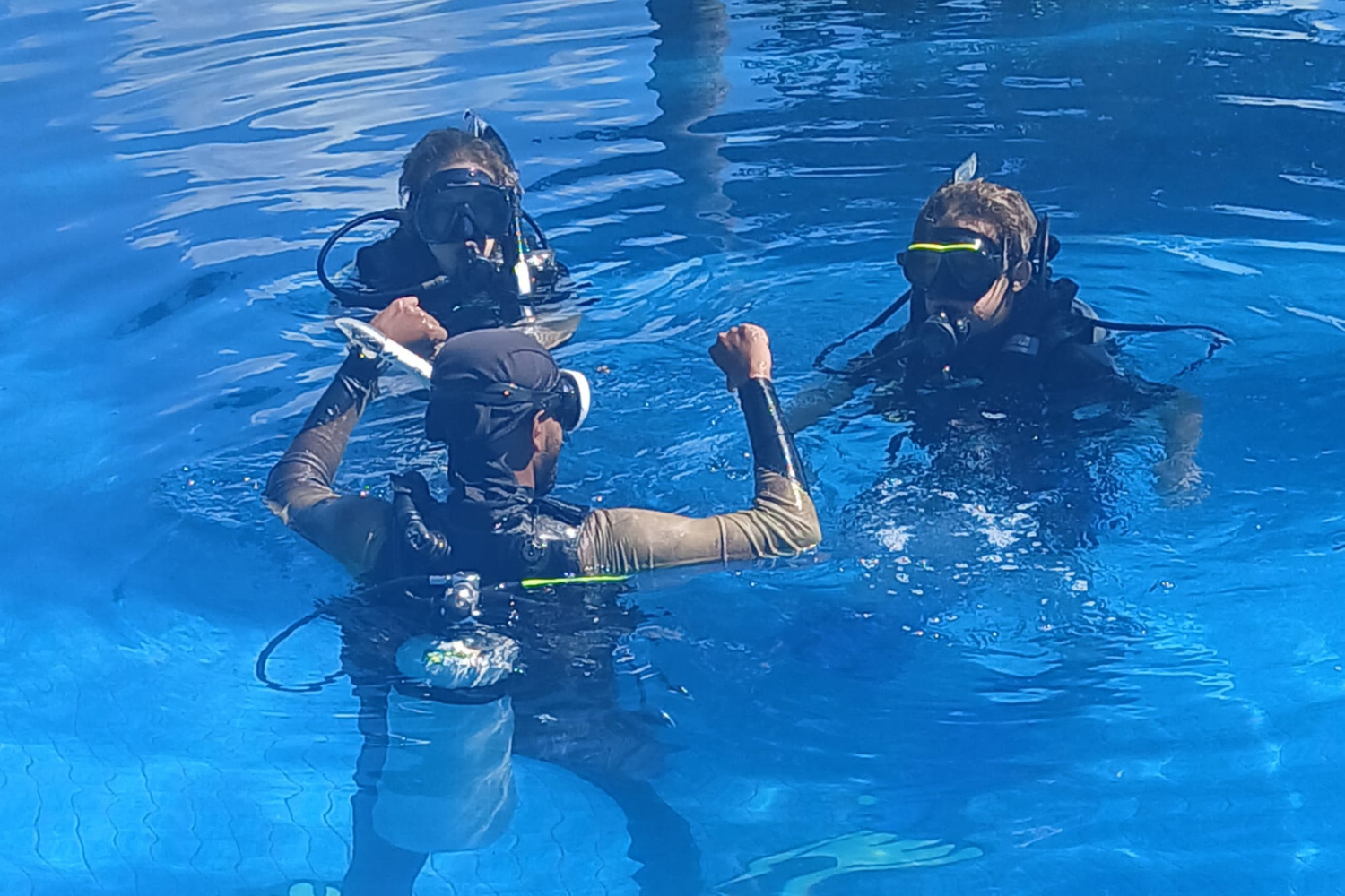 A group of scuba divers are swimming in a pool.