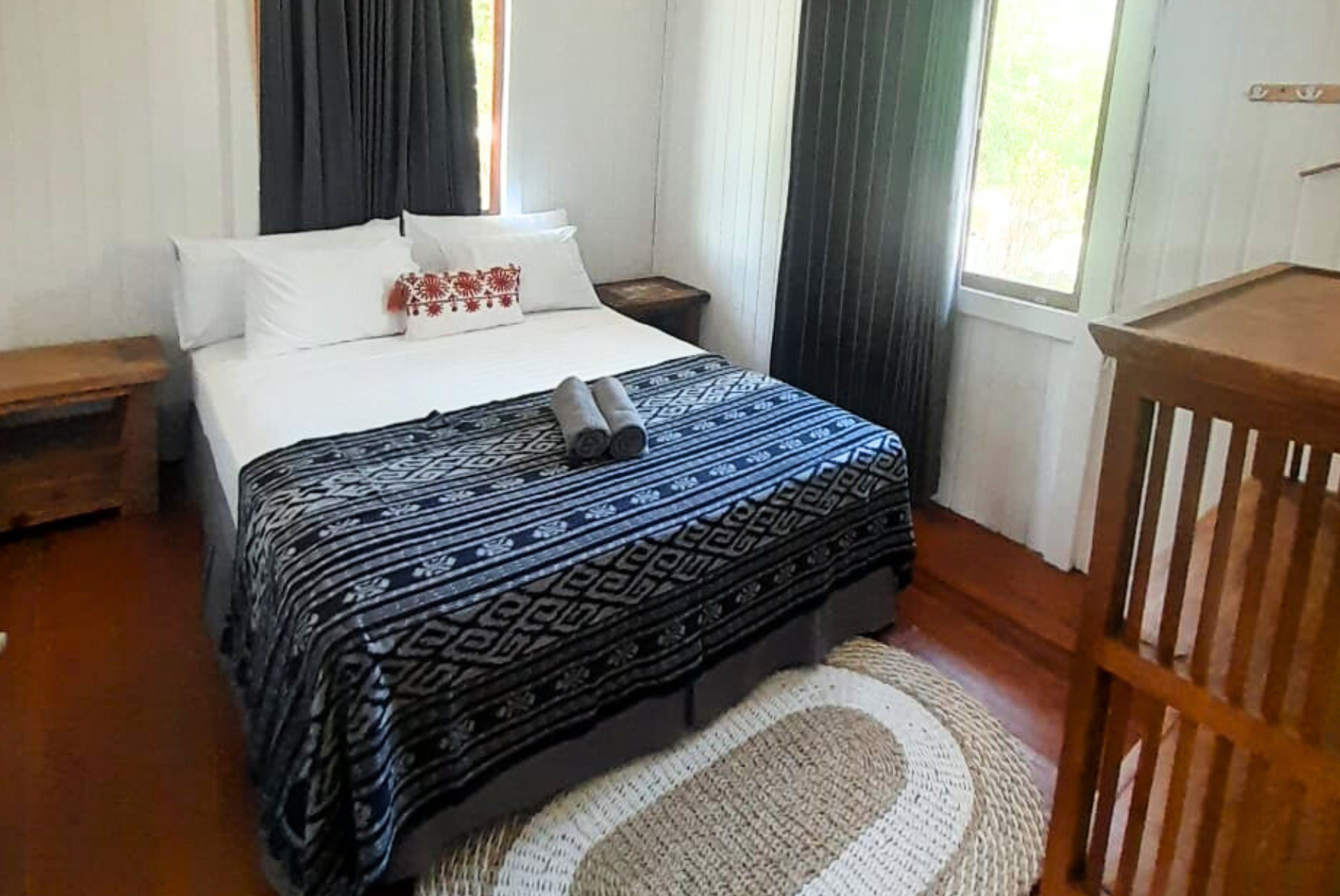 A bedroom with a bed , nightstand , rug and window.