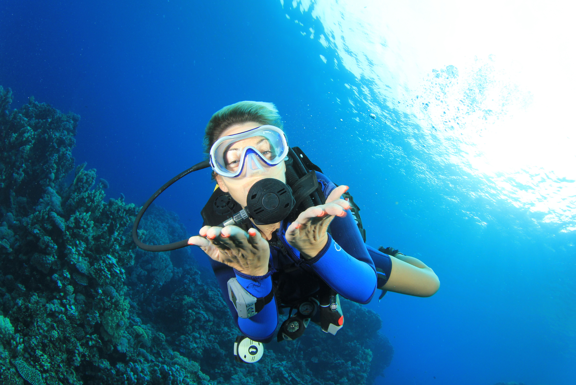 A scuba diver is swimming in the ocean near a coral reef.