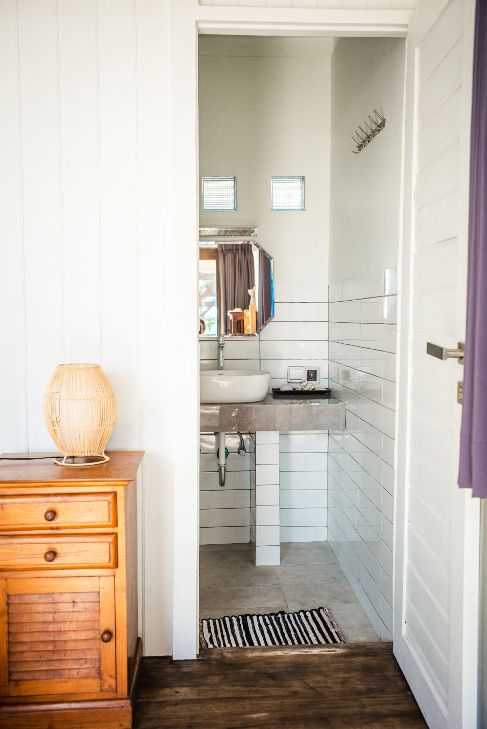 A bathroom with a sink , mirror , and wooden floor.