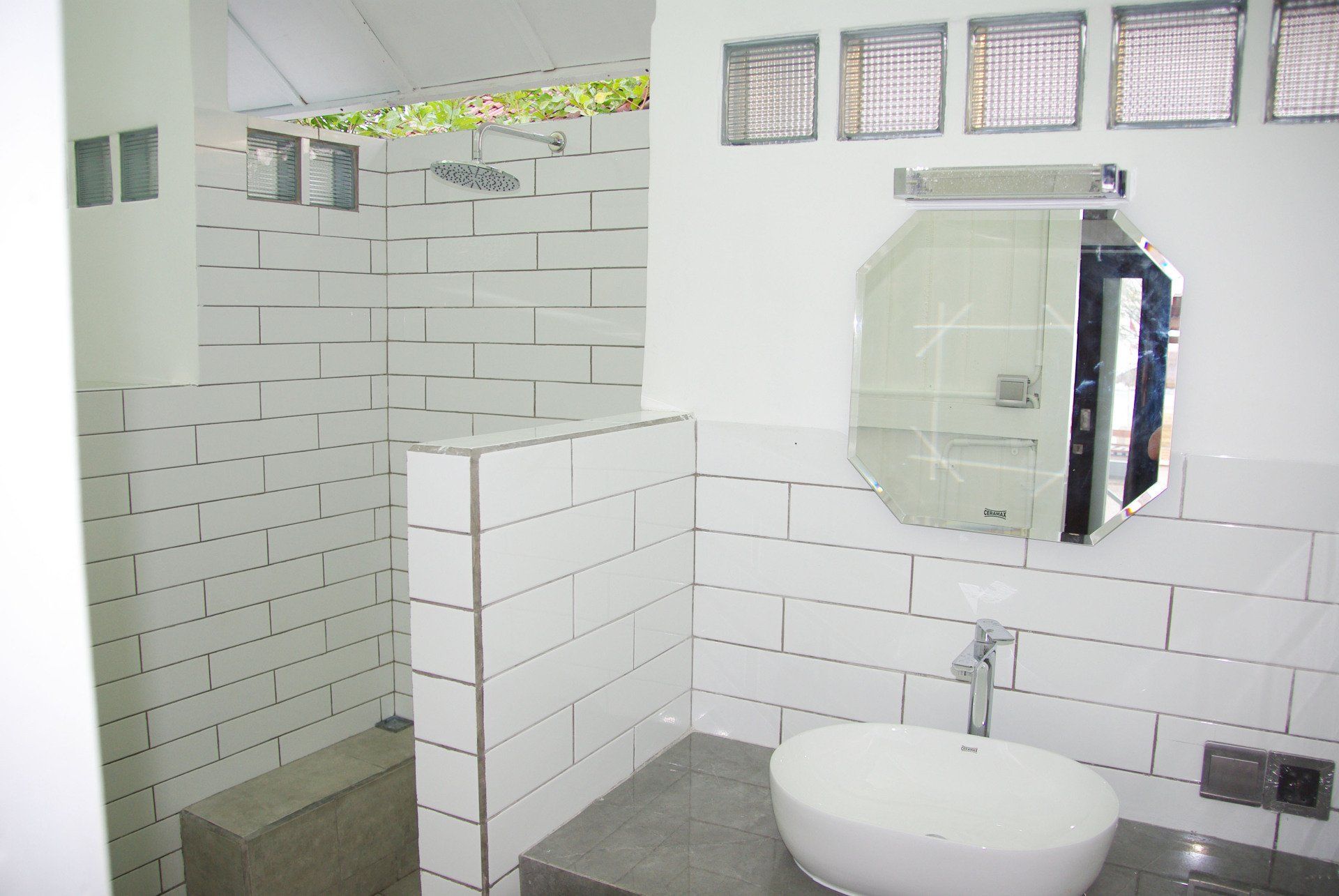 A bathroom with white tiles and a sink and mirror