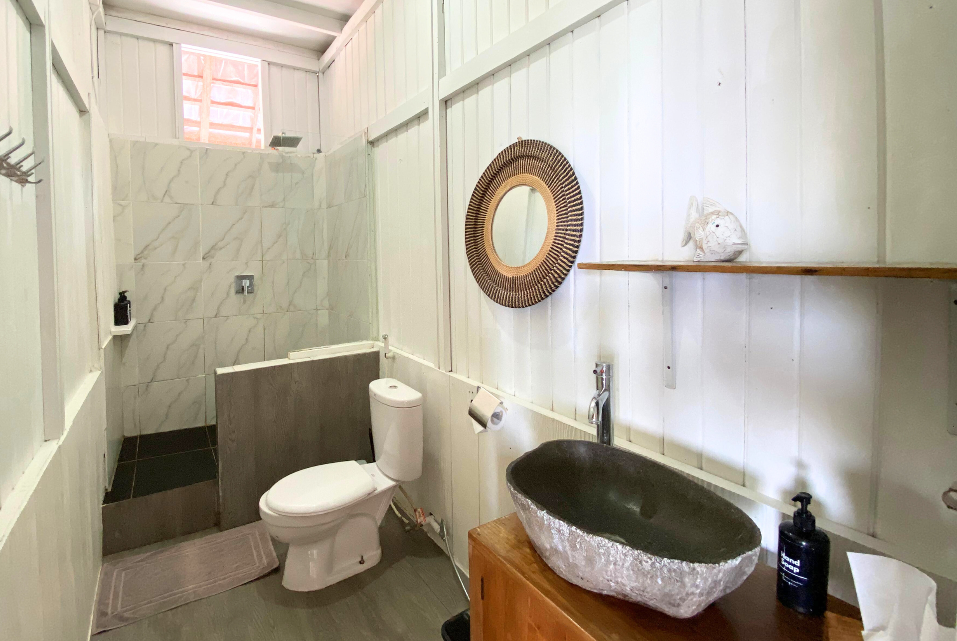 Bathroom with white walls, toilet, gray sink, and mirror.