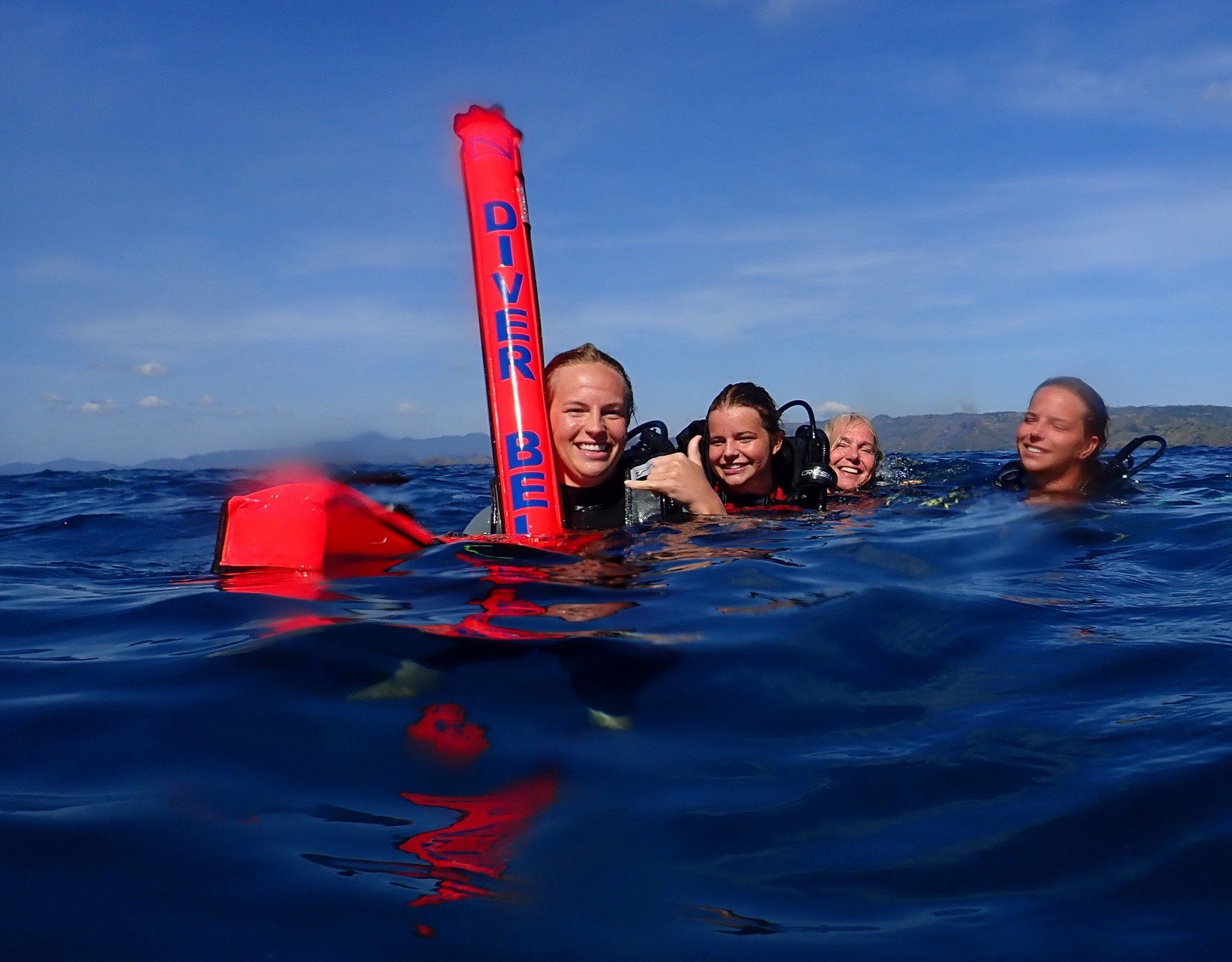 A group of people are swimming in the ocean holding a red buoy.