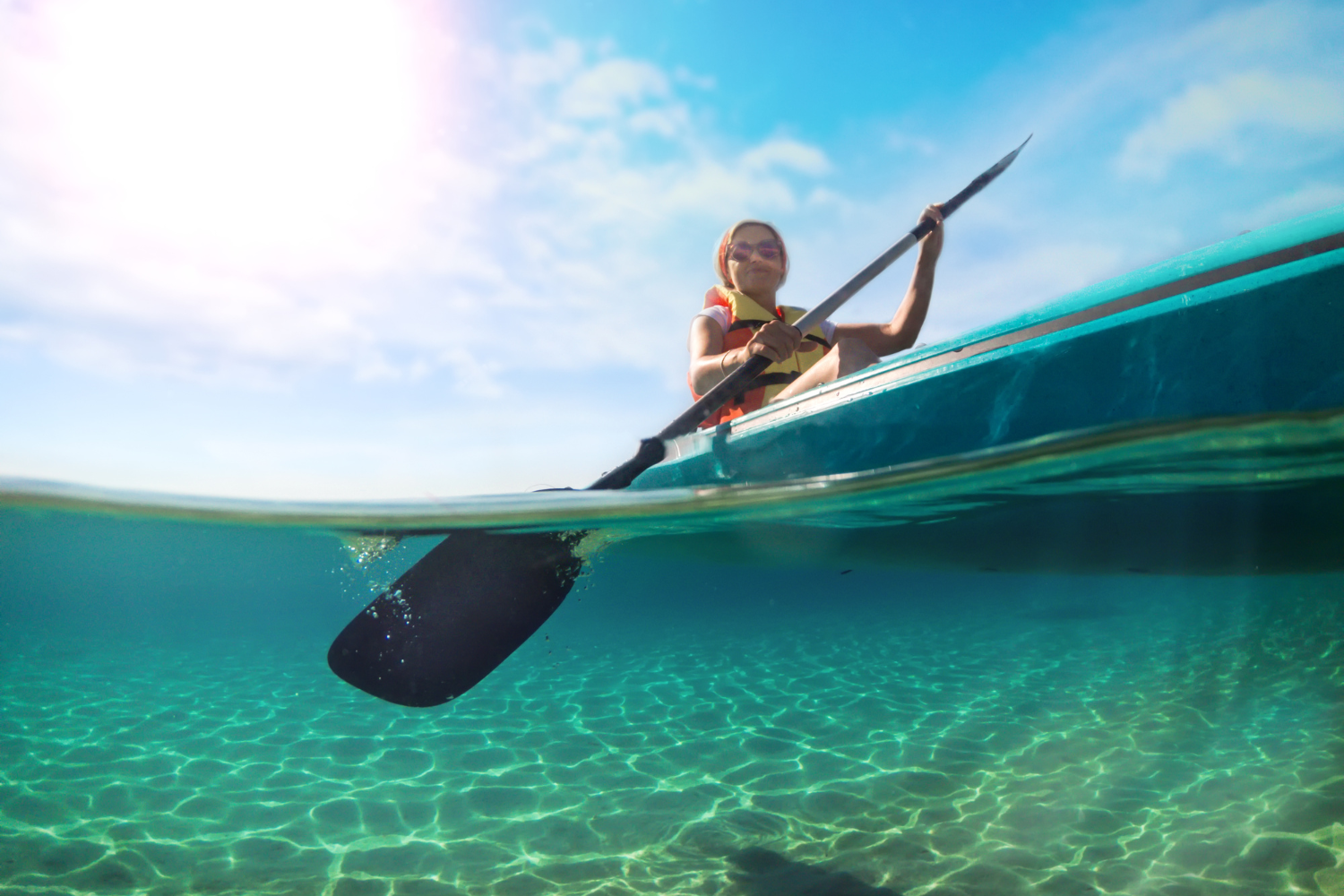 A woman is paddling a kayak in the ocean.