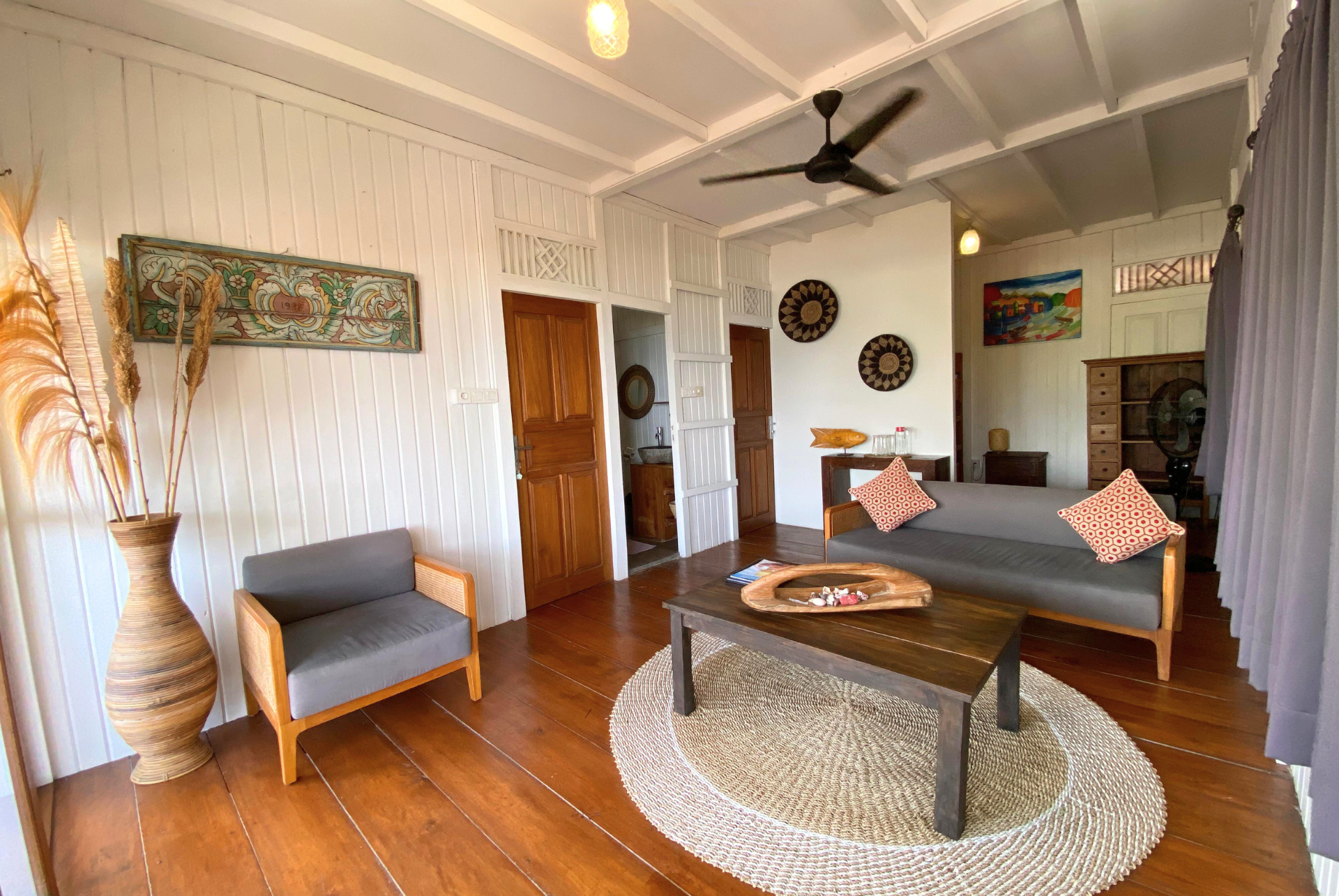 Living room with wooden floors, white walls, gray furniture, and decorative items.