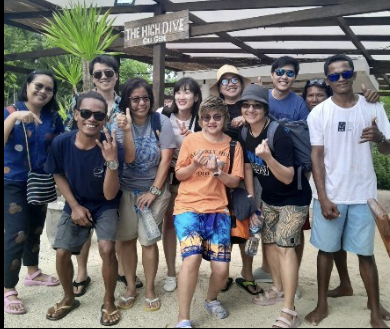 A group of people standing in front of a sign that says the beach dive