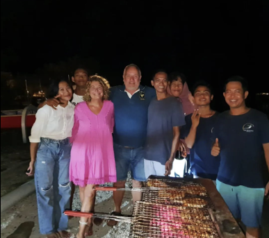 A group of people posing for a picture in front of a grill