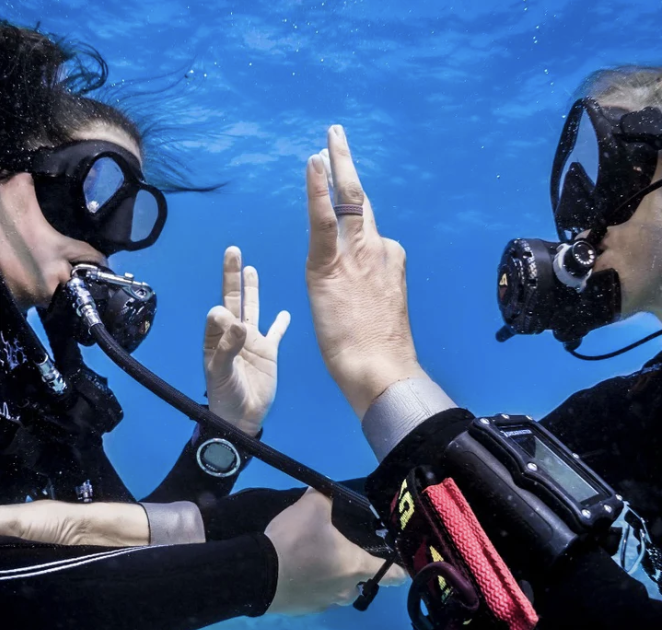 Two scuba divers are giving each other a high five