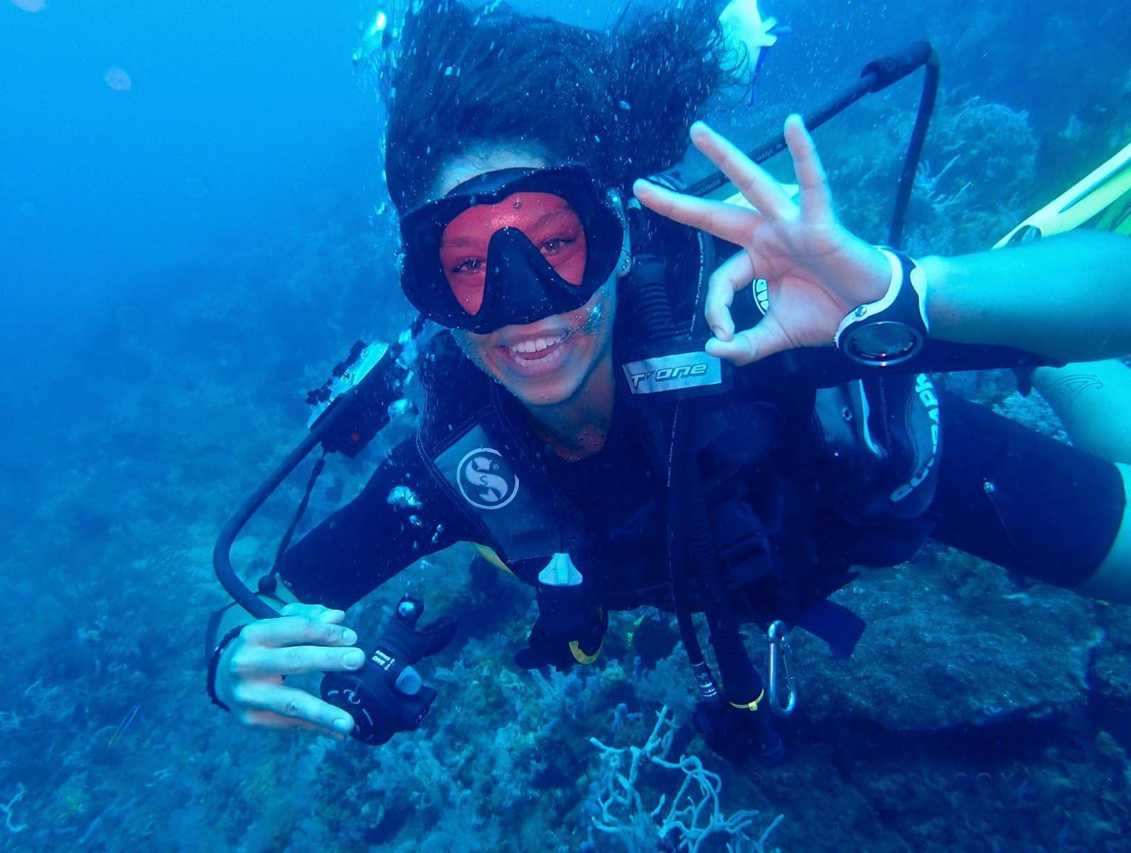 A scuba diver is giving the ok sign in the ocean