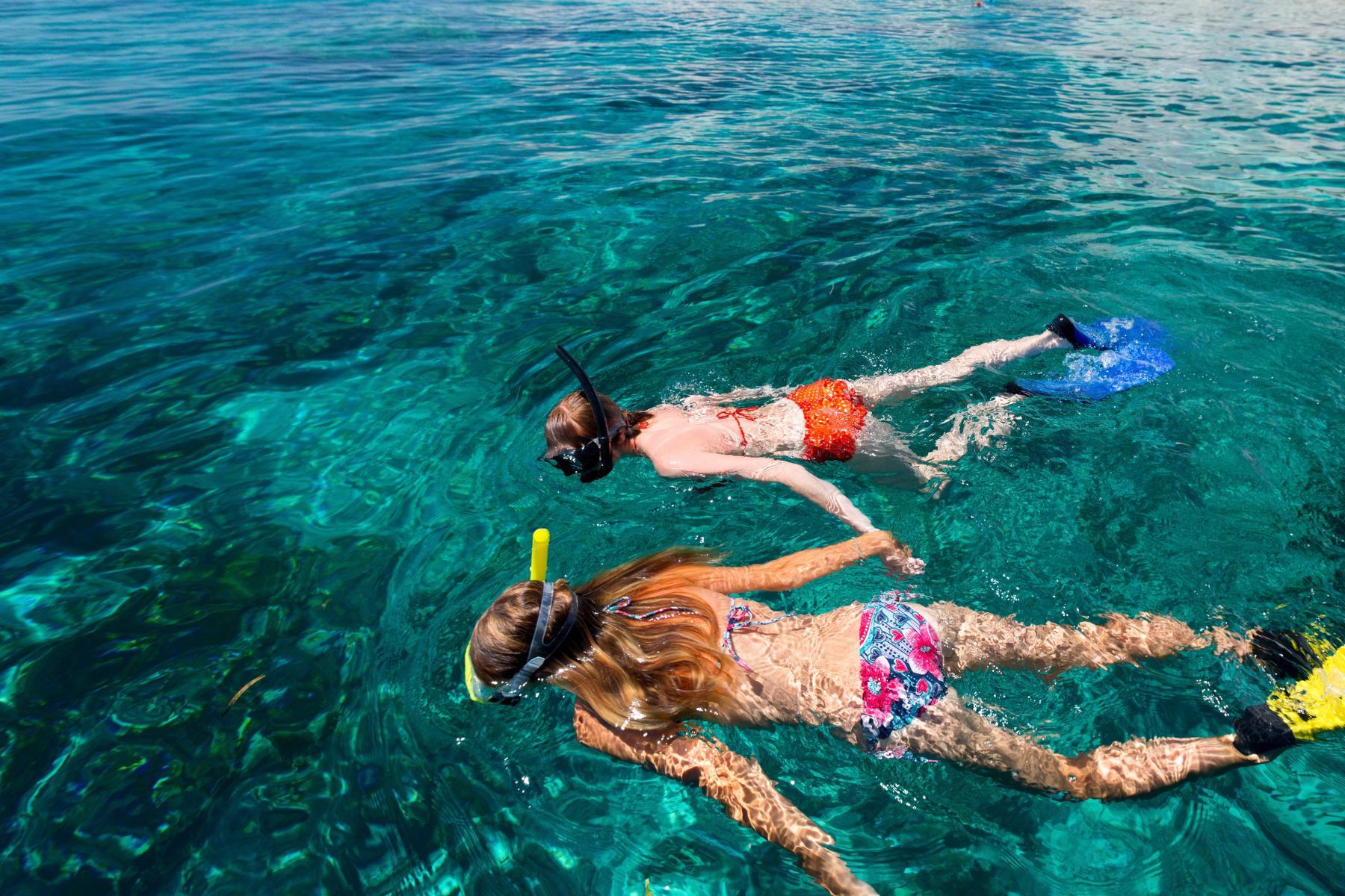 A boy and a girl are swimming in the ocean.