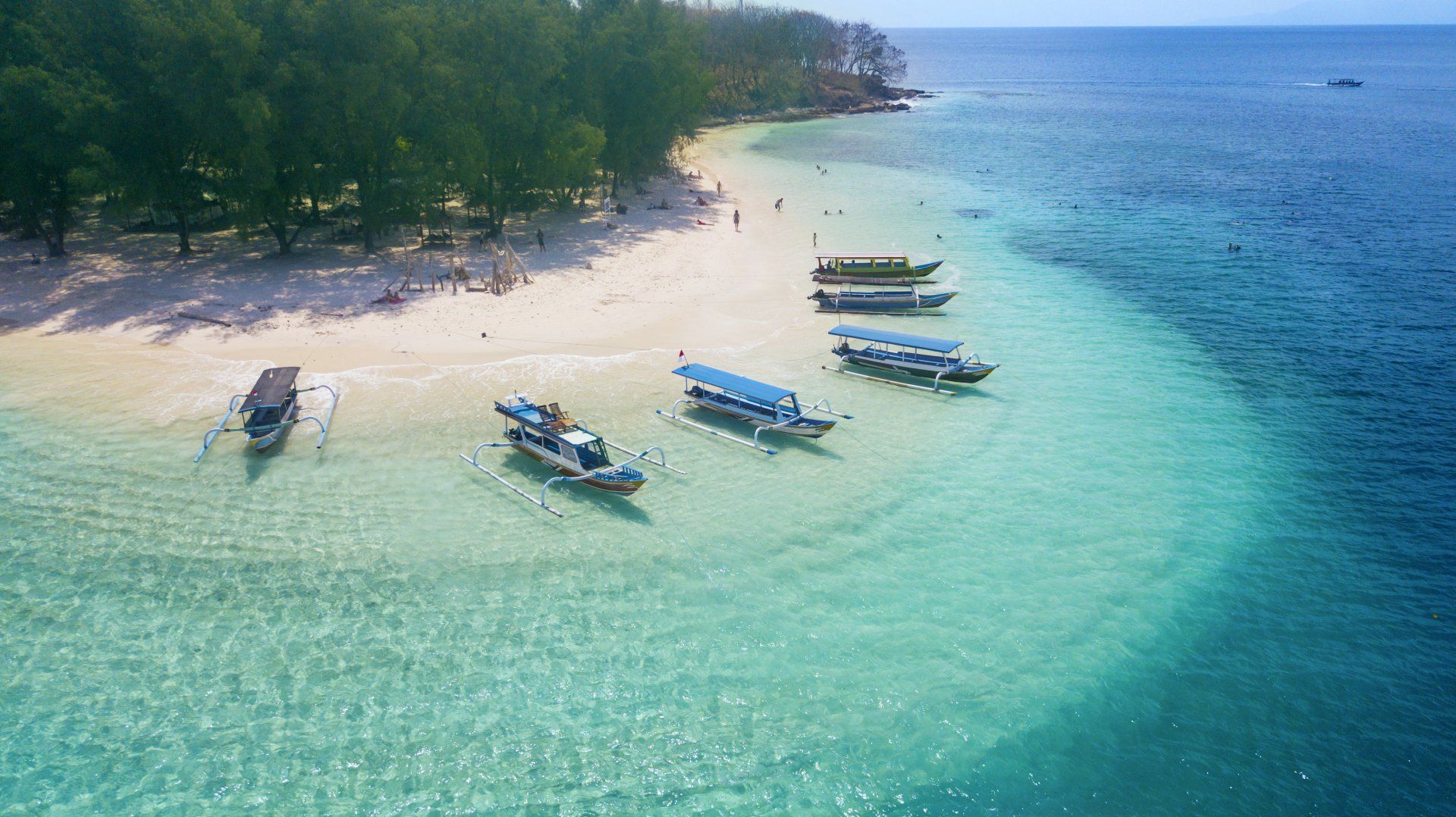 An aerial view of a beach with boats in the water.
