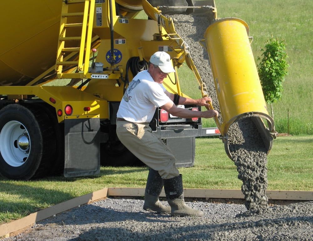 A Man Is Pouring Concrete from A Yellow Truck — Maslin Concrete Pumping in Dubbo, NSW