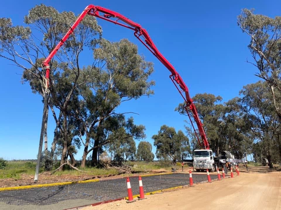 A Concrete Pump Is Being Used to Pour Concrete on A Dirt Road — Maslin Concrete Pumping in Cowra, NSW