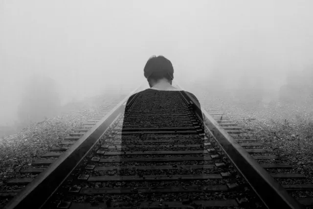 A person standing alone looking down railroad tracks