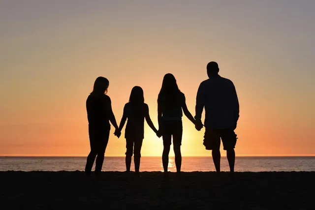 Family watching the sunset together holding hands