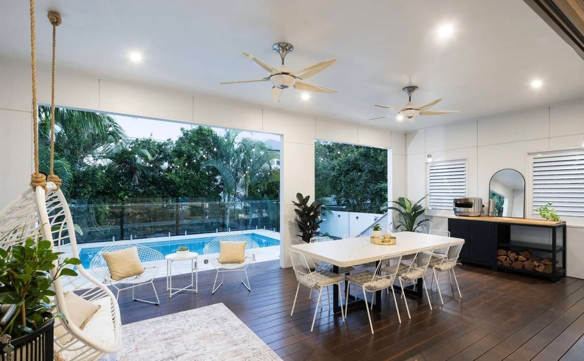 A Bright, Open-air Patio Featuring a Dining Set and Pool View on a Wooden Deck — OHMY Electrical Contractors in Carina, QLD