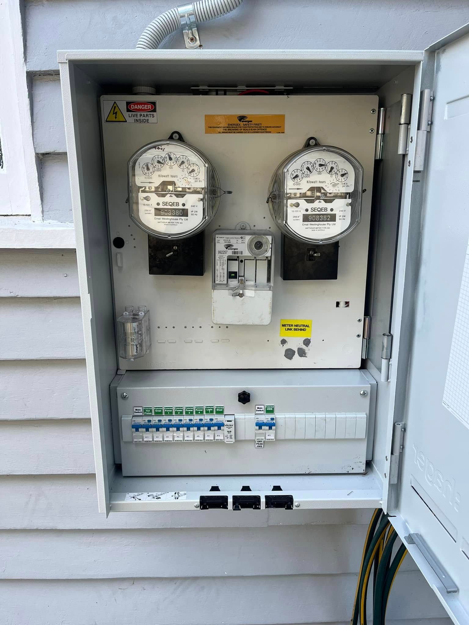 An Open Outdoor Electrical Meter Box Mounted on a White Siding Wall — OHMY Electrical Contractors in Carina, QLD