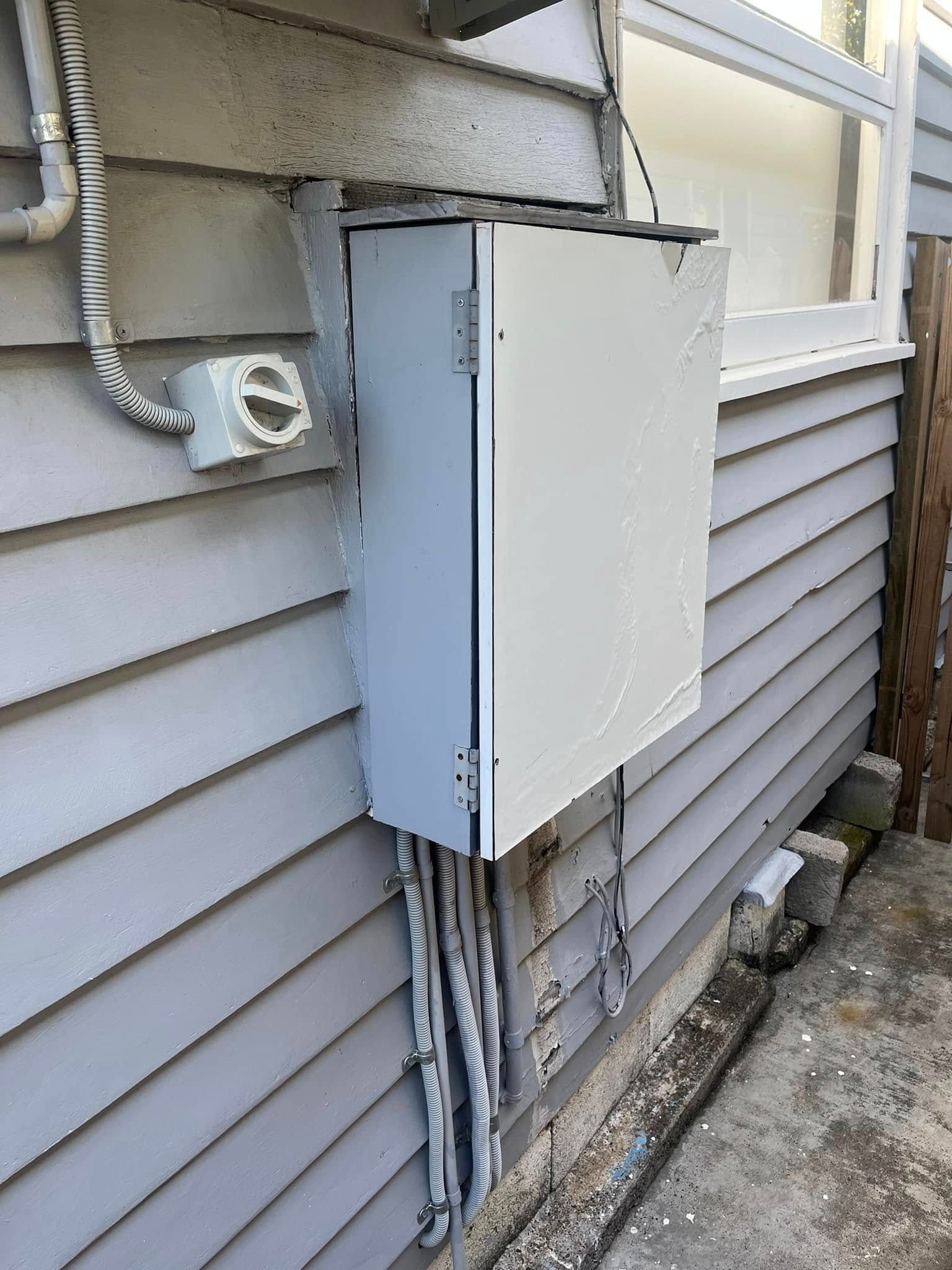 A Grey Electrical Box Mounted on the Exterior Wall of a House — OHMY Electrical Contractors in Camp Hill, QLD
